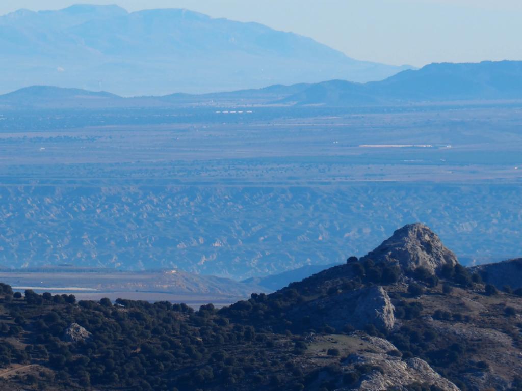 Die zerfurchten, rötlichen Badlands von Guadix in der Ferne.
